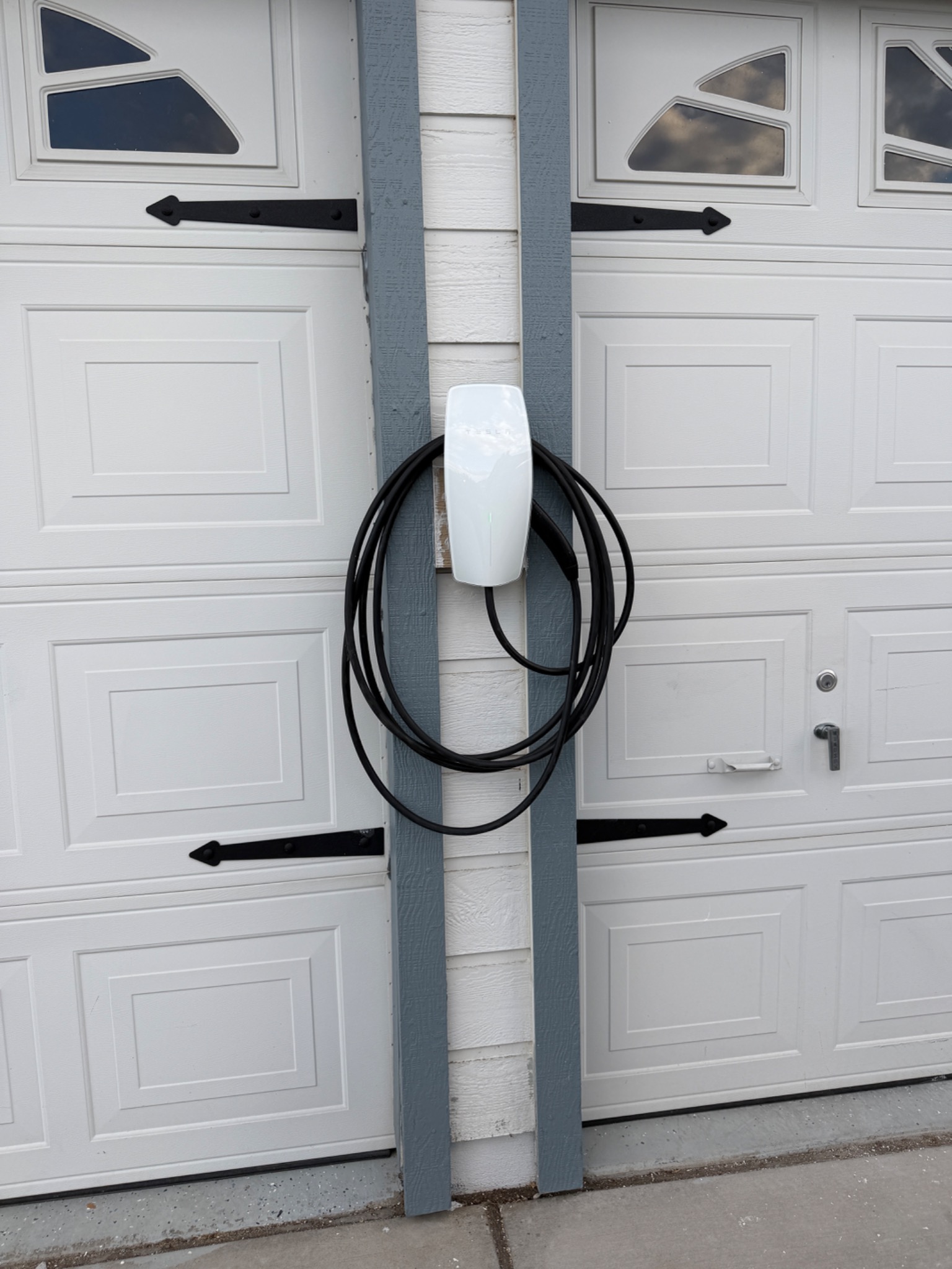 Tesla Wall Connector relocated to the exterior wall between closed garage doors at a West Reno home